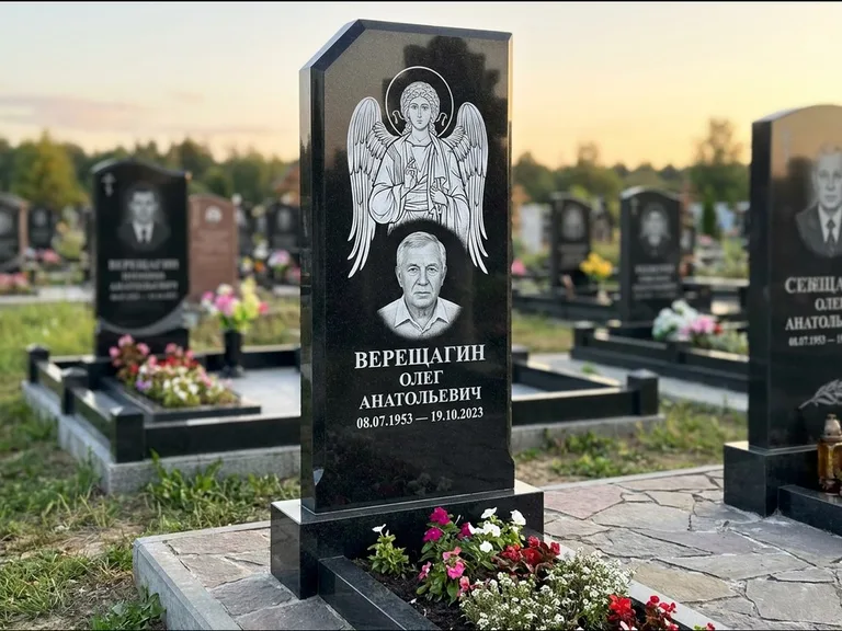 Памятник с гравировкой иконы: стела с резным навершием и нимбом в золоте — гравировка образа Спасителя, высокие разросшиеся туи полукругом, работа «Мельникова» в Ставрополе