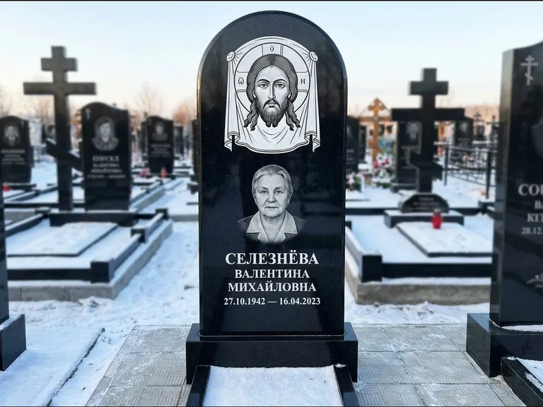 Памятник с гравировкой иконы: небольшая скромная одиночная стела с именной иконой — золочёный нимб на образе, аккуратный участок с газоном, работа «Ковалёв» в Ставрополе