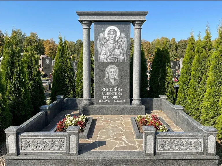 Памятник с гравировкой иконы: массивная стела с двускатным навершием-домиком — гравировка Николая Чудотворца, живая изгородь из туи, работа «Журавлёв» в Ставрополе
