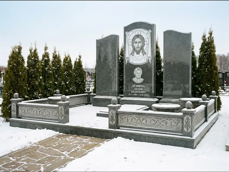 Памятник с гравировкой иконы: узкая вертикальная стела-пилон с ликом — икона в резной рамке-киоте, открытая лужайка без ограды, работа «Одинцов» в Ставрополе