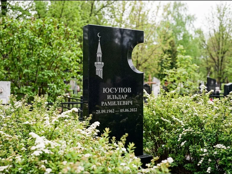 Мусульманский памятник с гравировкой мечети: стела с боковым вырезом в форме полумесяца — гравировка минарета с полумесяцем, низкие кусты спиреи в цвету, работа «Юсупов» в Ставрополе